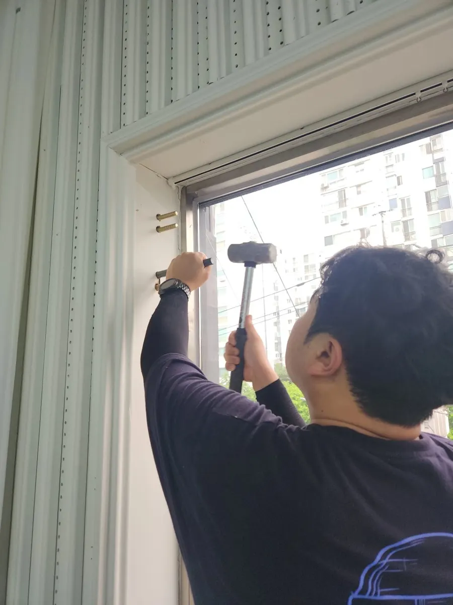 평택 완강기 설치 업체 벽 앵커 작업 중 망치질하는 모습